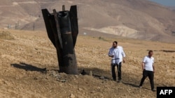 Two men examine a missile half-buried in the ground on the outskirts of Jericho on June 8 following Iranian strikes. 