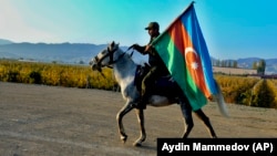 An Azerbaijani soldier with a national flag rides a horse in Ganca, Azerbaijan's second-largest city, near the border with Armenia, on November 10.