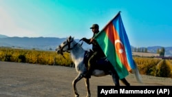 Азербайджанский военный верхом на лошади держит флаг своей страны. Гянджа, второй по величине город Азербайджана, расположенный недалеко от границы с Арменией. 10 ноября 2020 года.