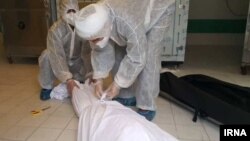 Workers in protective suits preparing body of coronavirus victim for removal. 