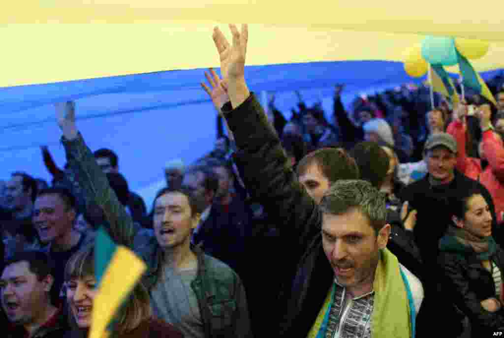 Ukrainians hold up a large national flag and shout slogans as they take part in a nationalist and pro-unity rally in the eastern city of Donetsk.(AFP/Anatoly Stepanov)