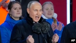 Russian President Vladimir Putin gestures while addressing a crowd at a concert marking his victory in a presidential election and the 10th anniversary of Russia's illegal annexation of Crimea on Red Square in Moscow on M arch 18. 