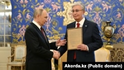 Russiýanyň prezidenti Wladimir Putin Gazagystanyň prezidenti Kasym-Žomart Tokaýewa onuň kakasy Kemel Tokaýewyň sylag kagyzyny gowşurýar. Moskwa, 9 maý 2025-nji ýyl