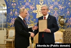 Орусия президенти Владимир Путин Касым-Жомарт Токаевге атасынын сыйлык баракчасын тапшырууда. 2025-жылдын 9-майы.