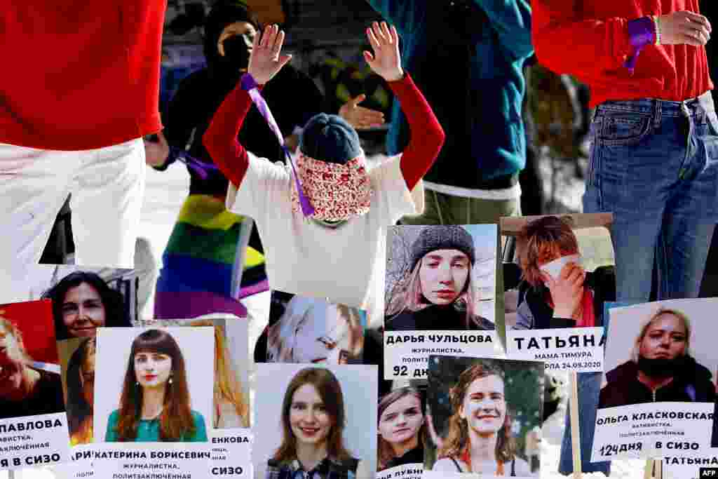 A feminist activist takes part in a flash mob with photographs of women imprisoned since the&nbsp; Belarusian presidential election on August 9, 2020, as they protest against police violence in Minsk on February 14. (AFP)