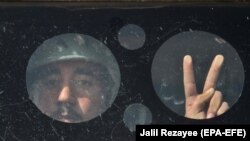 An Afghan Army soldier flashes the victory sign from an armored vehicle during a training session in Herat on September 24.