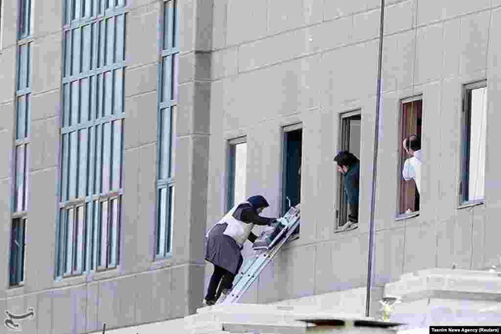 A woman is evacuated from the parliament building.&nbsp;