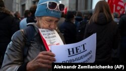 A demonstrator holds the Russian Constitution and a poster that reads: "No raising of the retirement age" during a protest in front of the Russian State Duma in Moscow on September 26.