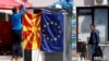 Nje djalë duke varur flamurin e Maqedonisë së Veriut dhe atë të BE-së.