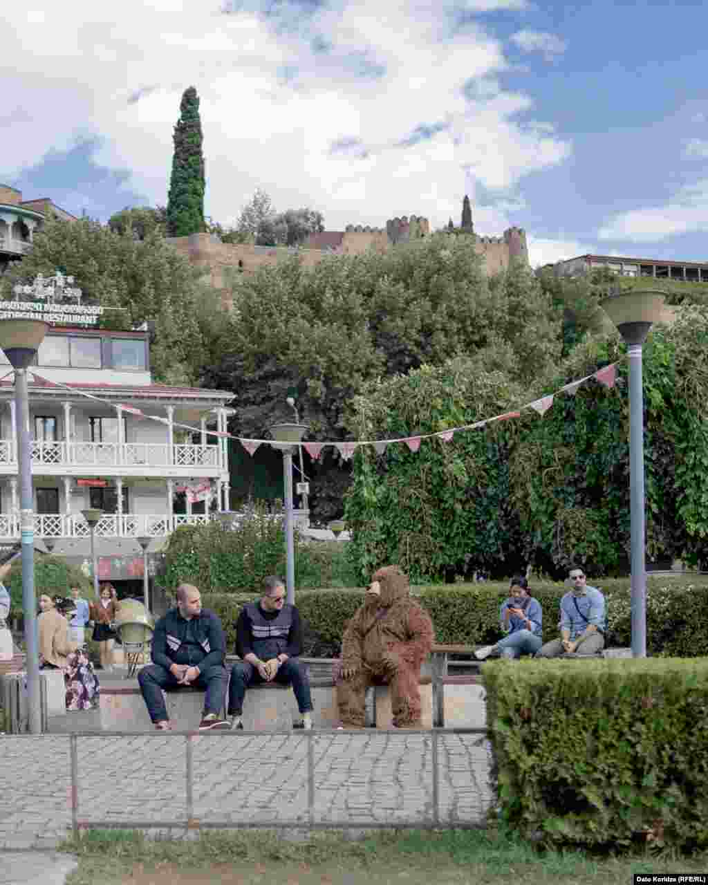 20 სექტემბერი, თბილისი - თბილისობაზე პოლიციელები და მსახიობი დასასვენებლად ერთ სკამზე ჩამოსხდნენ.ზეიმი 2025 წელს ძალიან ადრე, შუა სექტემბერში გაიმართა. ოპოზიციამ ეს იმით ახსნა, რომ ხელისუფლება შეეცადა წინასაარჩევნოდ თბილისელების გული მოეგო. რუსთაველის გამზირი დღესასწაულს გამოეთიშა, იქ პროევროპული დემონსტრაციები იმართებოდა.ფოტო: დავით ქორიძე