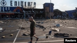 A man on July 26 walks past a shopping mall that was hit by a Russian missile in Ukraine's Dnipro region.