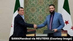 Udhëheqësi i SDF-së, Mazloum Abdi, dhe presidenti i përkohshëm i Sirisë, Ahmed al-Sharaa, pas arritjes së një marrëveshjeje më 10 mars 2025. 