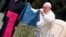 Pope Francis holds up a flag that was brought to him from Bucha, Ukraine, during his weekly general audience at the Vatican on April 6.