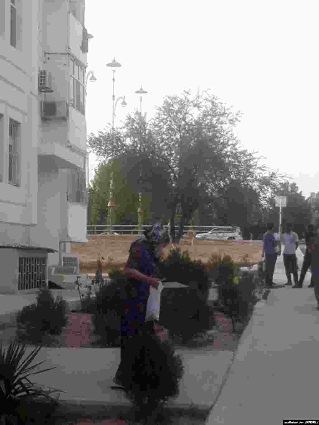 Ýaşaýyş jaýynyň öňünde gürleşip duran maskaly erkekler we geçip barýan aýal. Aşgabat, sentýabr, 2020.&nbsp;