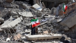 A man holds up an Iranian flag amid the debris of a destroyed building following air strikes in central Tehran on March 4.