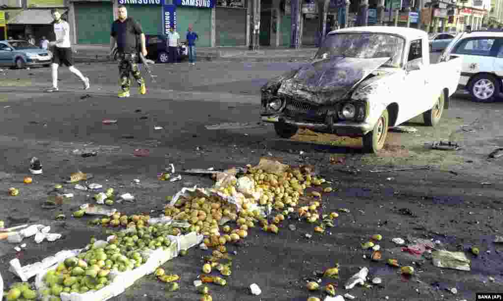 Syrians inspect the site of a suicide attack in Sweida, Syria. Syrian state media say dozens of people were killed in the attack in the country&#39;s south, blaming the bombing on Islamic State militants. (SANA via AP)