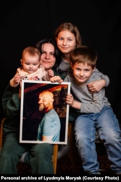 Людмила Моряк та її троє середніх дітей – Поліна, Макс та Мія разом із фотографією батька Мії – Сергієм
