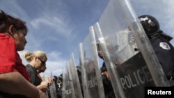 Protesters face a police barricade in front of a government building in Pristina on October 17.