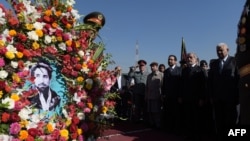 Afghan Chief Executive Officer Abdullah Abdullah (second right) watches as a soldier carries a wreath with a photo of slain Afghan national hero Ahmad Shah Masud during an event marking the 15th anniversary of his death on September 8 in Kabul.