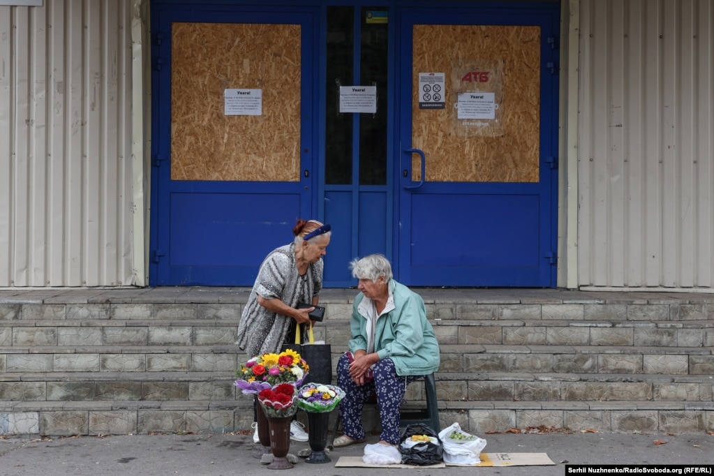 Gratë duke shitur lule dhe perime pranë një dyqani të madh të mbyllur. Në Pokrovsk, të gjitha dyqanet e mëdha dhe qendrat tregtare janë të mbyllura. Vetëm dyqanet e vogla ushqimore mbeten të hapura.