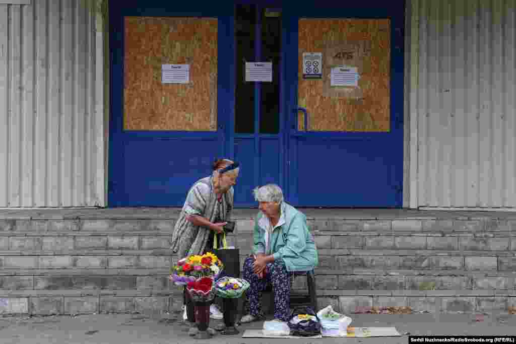 Gratë duke shitur lule dhe perime pranë një dyqani të madh të mbyllur. Në Pokrovsk, të gjitha dyqanet e mëdha dhe qendrat tregtare janë të mbyllura. Vetëm dyqanet e vogla ushqimore mbeten të hapura.