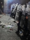 Demonstrant sa gas maskom udara po štitovima policajaca u kordonu u Novom Sadu. 5. septembar 2025. 
