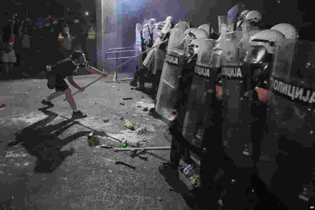 Demonstrant sa gas maskom udara po štitovima policajaca u kordonu u Novom Sadu. 5. septembar 2025.