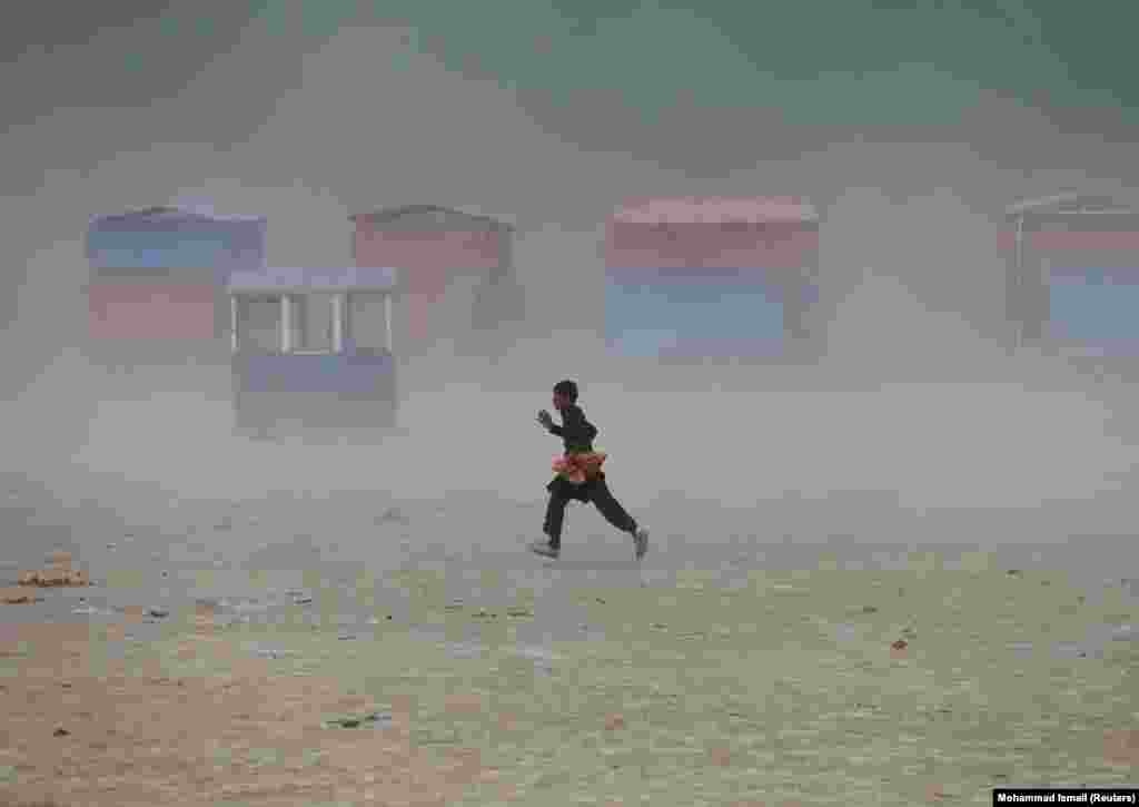 Мальчик бежит во время пыльной бури на озере Карга на окраине Кабула
