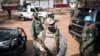 A UN peacekeeper (right), a private Russian security guard (center), and a member of the presidential guard (left), stand guard while Central African Republic President Faustin Archange Touadera is at polling station on December 27, 2020. 