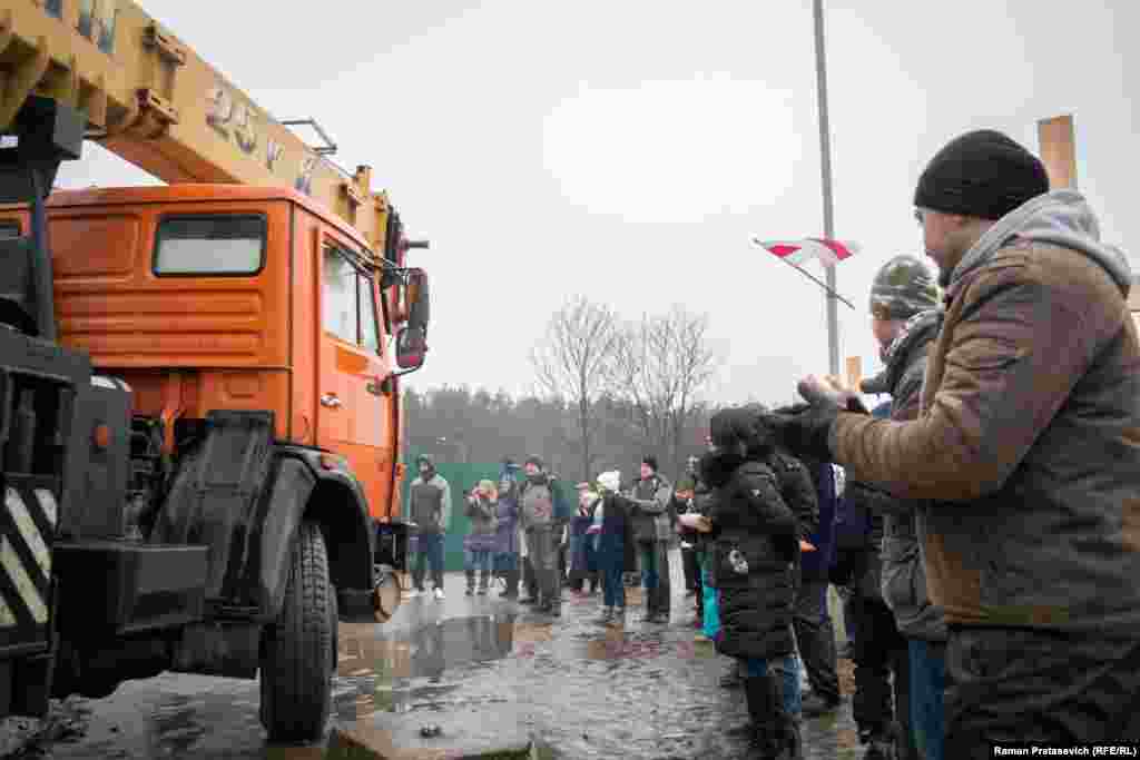 Людзі апладзіруюць, калі будаўнічая тэхніка пакідае будоўлю.