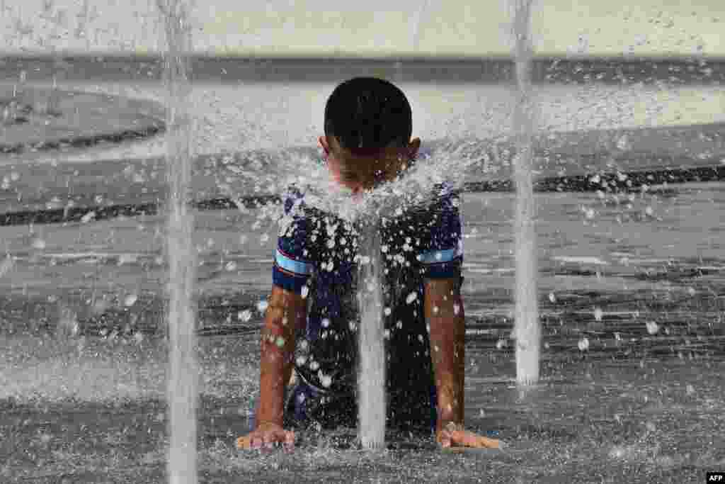 A child cools off in a fountain in Milan on July 24 as a major heatwave spreads throughout Europe with temperatures hitting nearly 40 degrees Celsius. (AFP/Giuseppe Cacace)