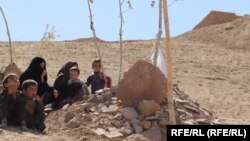 اعضای خانواده نگار پولیس زن در غور که از سوی افراد مسلح ناشناس به قتل رسید برای اتحاف دعا به روح او بالای قبرش آمده اند.