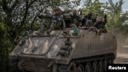 Украински войници карат бронетранспортьор близо до фронтовия град Бахмут.