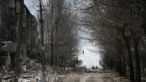 Місцеві жителі йдуть повз зруйновані російськими обстрілами будинки у Покровську, 12 квітня 2025 року
