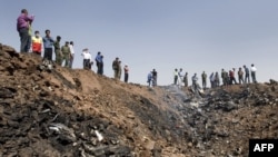 Iranians gather at the edge of a crater at the crash site of the Caspian Airlines plane, which fell into farmland near the city of Qazvin, northwest of Tehran.