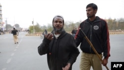 A Pakistan policeman, right, detains a cleric after a ceremony marking the death anniversary of provincial Governor Salman Taseer in Lahore on January 4.