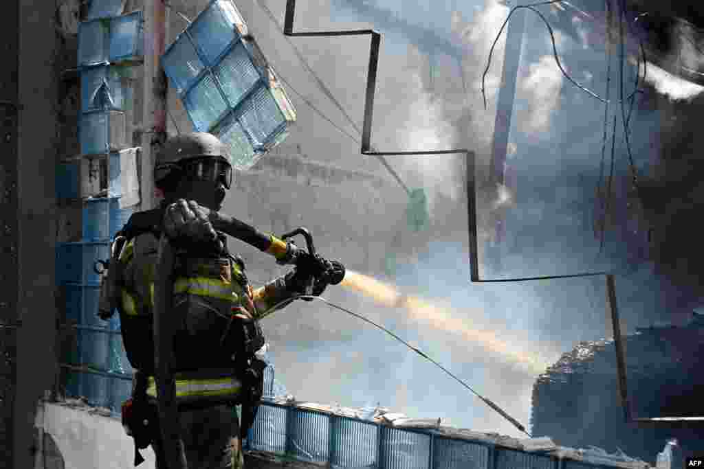 A Ukrainian rescuer works to extinguish a fire at the site of an aerial attack on Kharkiv.