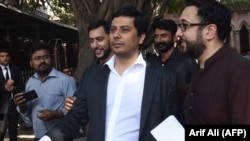 Pakistani journalist Cyril Almeida (center) arrives at the High Court to face treason charges in Lahore on October 8.