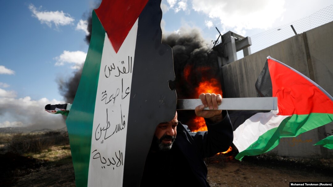 WEST BANK -- A demonstrator carries a model of a map with the colors of the Palestinian flag reading "Jerusalem is the eternal capital of Palestine" during a protest against the U.S. President Donald Trump's Middle East peace plan, in the village of Bili