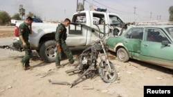 Iraqi security personnel inspect the site of a bomb attack in Kirkuk on October 24, where a child was killed.