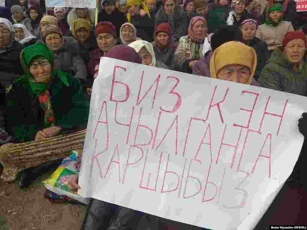 Жергиликтүүлөр кытай компаниясына нааразы пикирлер жазылган плакаттарды кармап турушат.