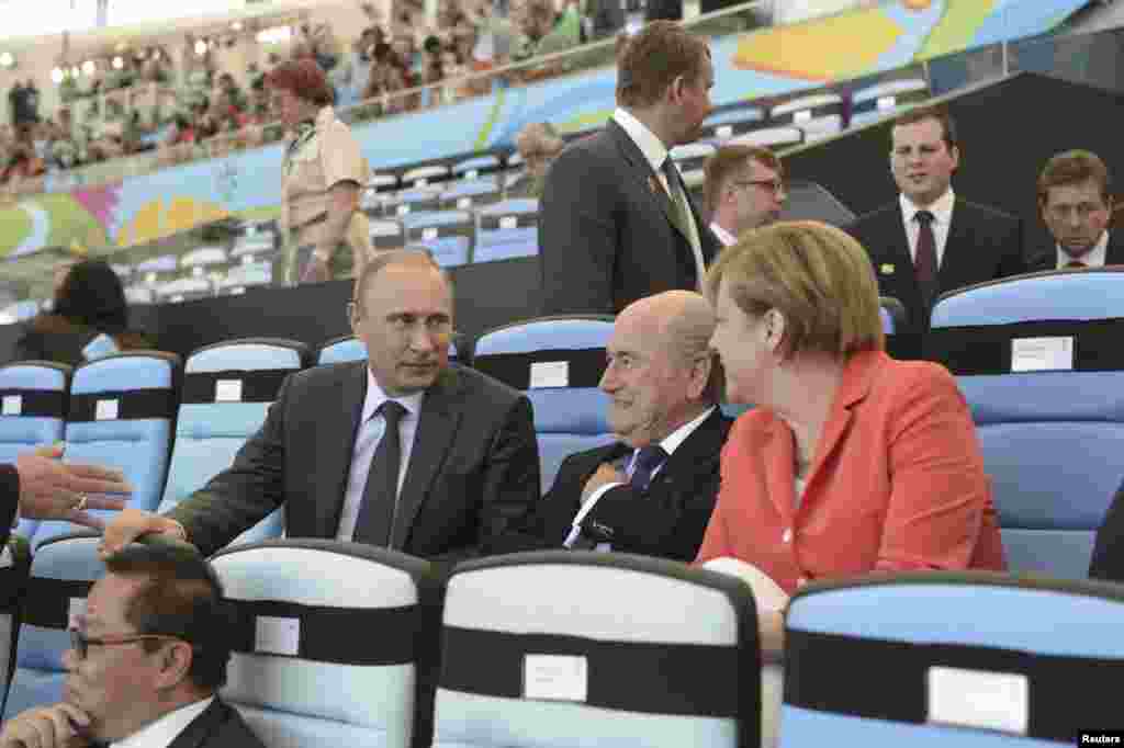 Russian President Vladimir Putin speaks to FIFA President Sepp Blatter and German Chancellor Angela Merkel during the 2014 World Cup final between Germany and Argentina at the Maracana stadium in Rio de Janeiro on July 13, 2014.