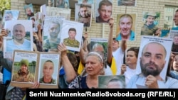 Рідні тих, хто ймовірно утримується в російському полоні, тримають їхні фото в надії, що хтось із звільнених їх упізнає і щось повідомить про їхню долю. Україна. Обмін 14 серпня 2025 року