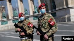 Hungarian military police officers patrol Budapest's deserted Heroes' Square during a coronavirus emergency. 