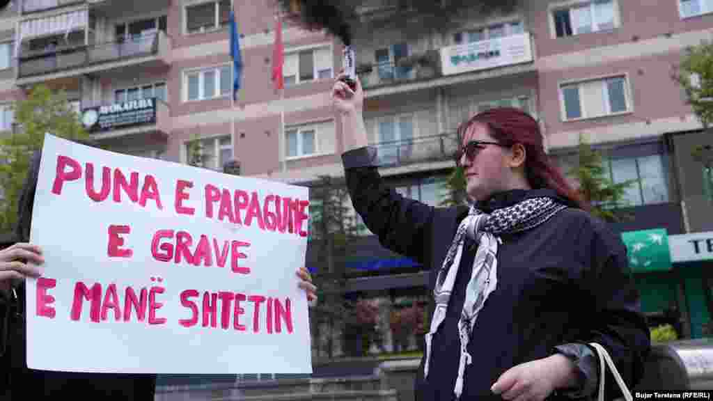 Žena drži transparent s natpisom: "Neplaćeni rad žena održava državu", tokom protesta na glavnom trgu u Prištini 1. maja.Žene na Kosovu snose najveći teret brige, provodeći i do šest sati dnevno u neplaćenom radu na njezi, što dodatno produbljuje rodni jaz.