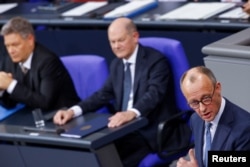 Liderul conservatorilor germani, Friedrich Merz (dreapta), vorbind în Bundestag înaintea votului de neîncredere în cancelarul social-democrat, Olaf Scholz (centru), pe 16 decembrie 2024