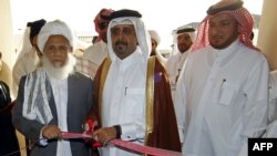 FILE: Former Qatari Assistant Minister for Foreign Affairs Ali bin Fahd al-Hajri (C) cuts the ribbon alongside a member of the Taliban's office Jan Mohammad Madani (L) at the opening ceremony of the new Taliban political office in Doha in 2013.