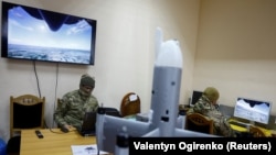 Инструктор и сотрудник частного охранного предприятия используют тренажеры для обучения полетам на беспилотнике-перехватчике, Украина, 8 апреля 2026 года