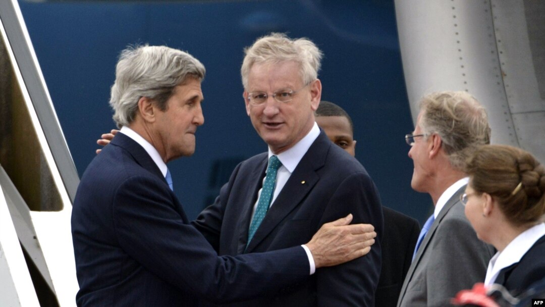 U.S. Secretary of State John Kerry (left) speaks with Swedish Foreign Minister Carl Bildt (center) as he arrives in Stockholm.