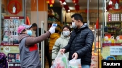 Супермаркетте тұтынушылардың температурасын тексеріп тұрған маман. Қытай, Хубэй провинциясы 7 ақпан 2020 жыл.